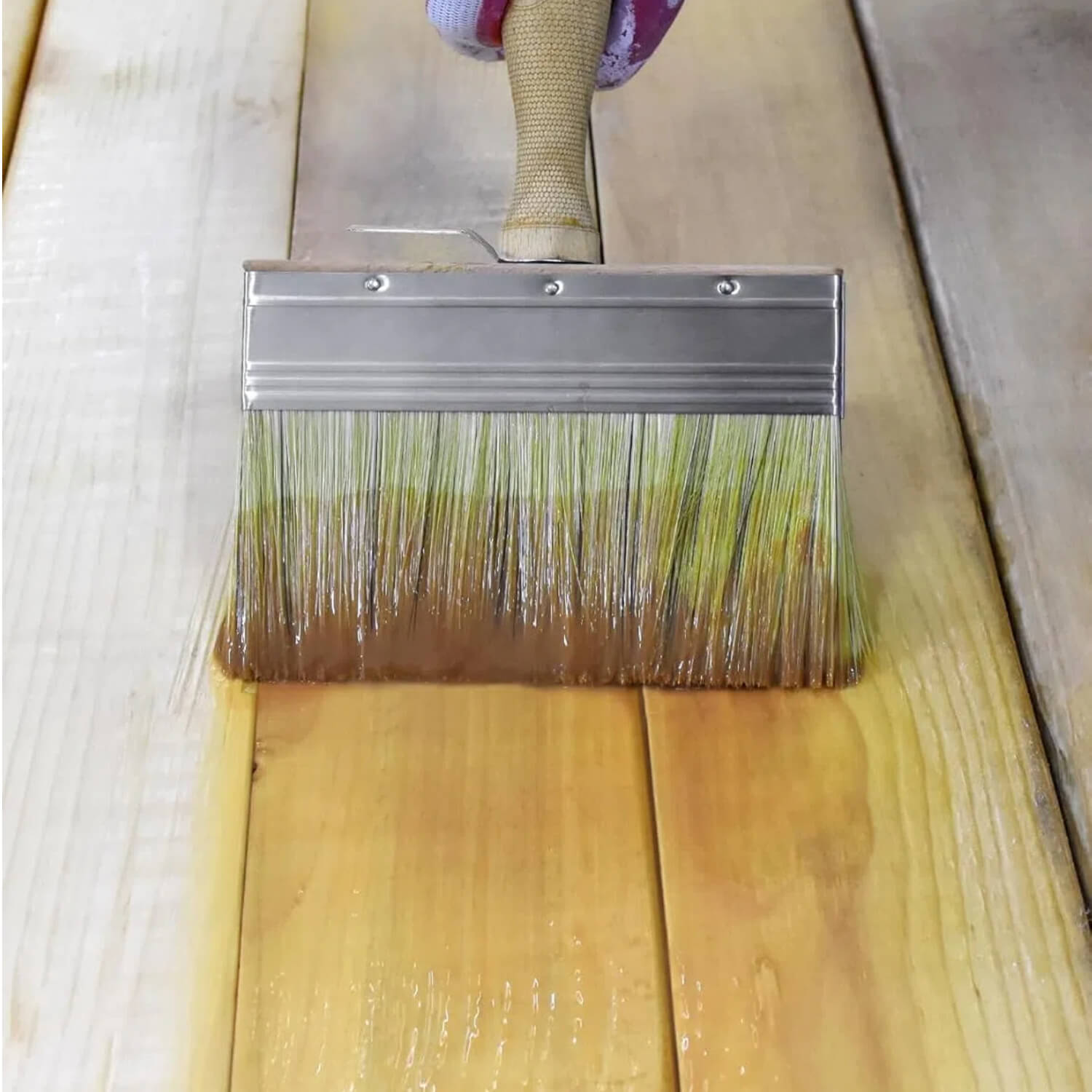 DIY painter using ROLLINGDOG limewash brush to apply wood stain on deck and fence