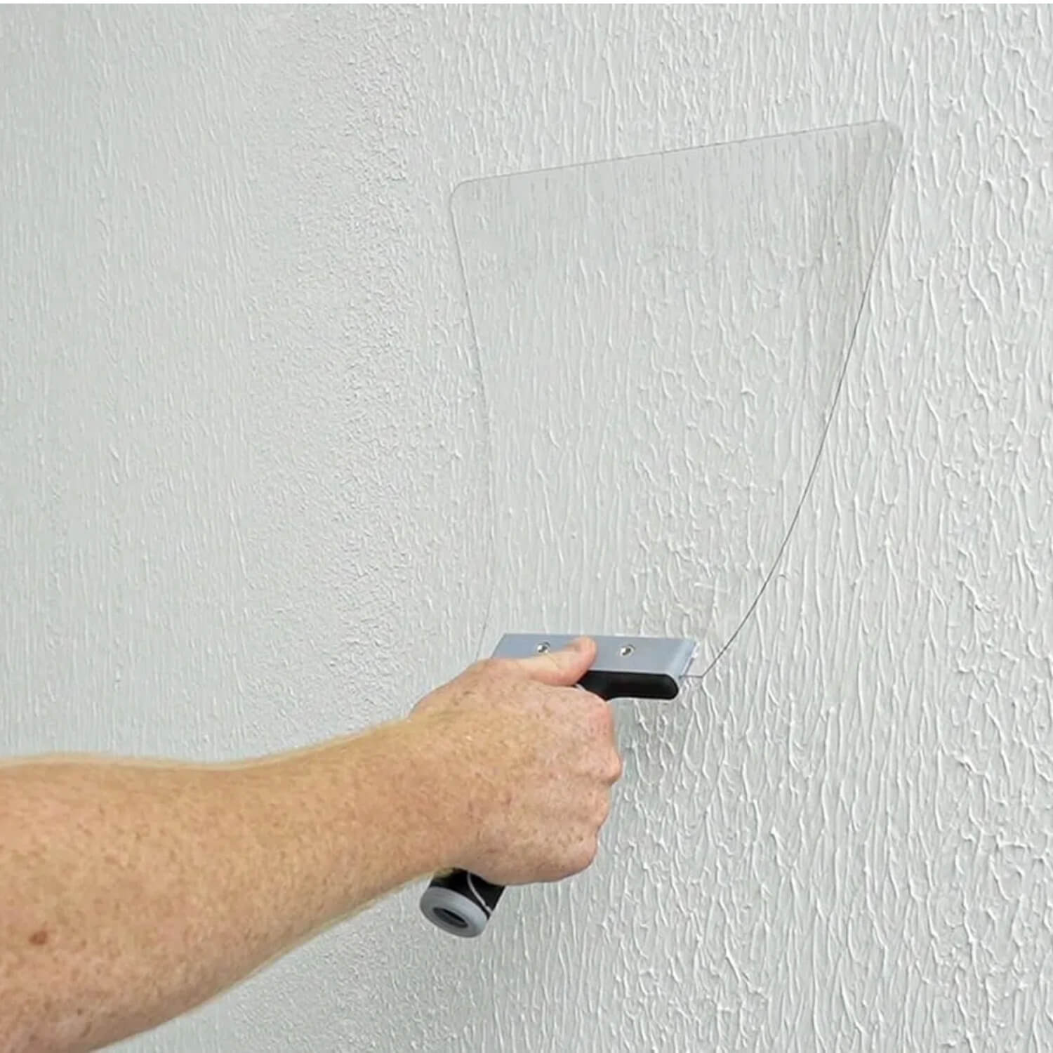 Knockdown knife in use spreading drywall compound to create even knockdown texture on wall surface